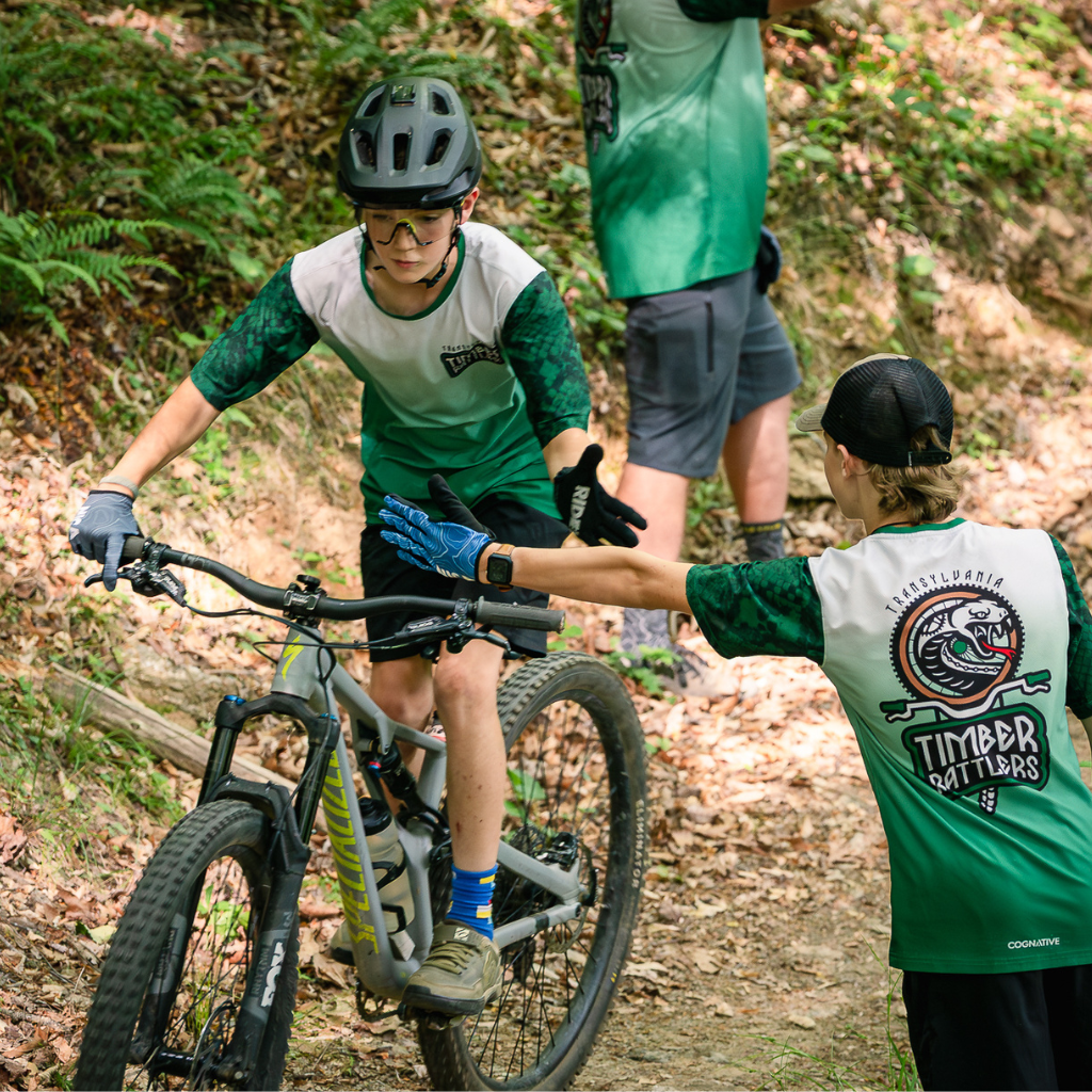 NICA riders in custom Transylvania Timber Rattlers jerseys high-fiving on the trail